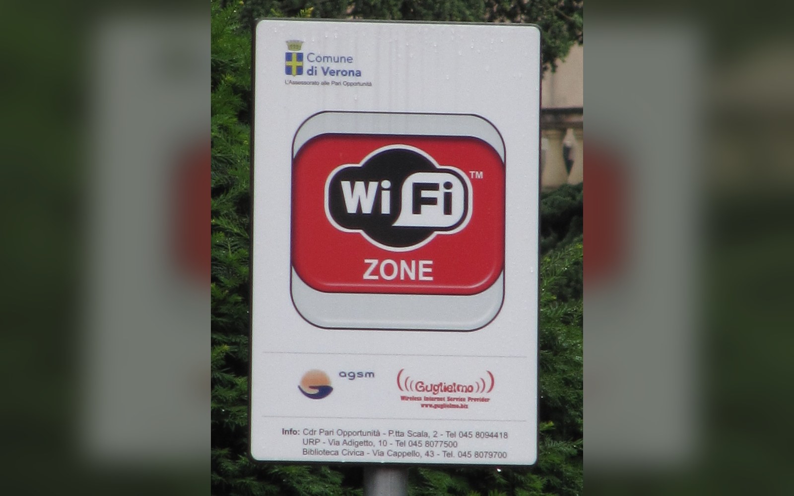 A public sign marking a wi-fi zone with municipal logos and contact information